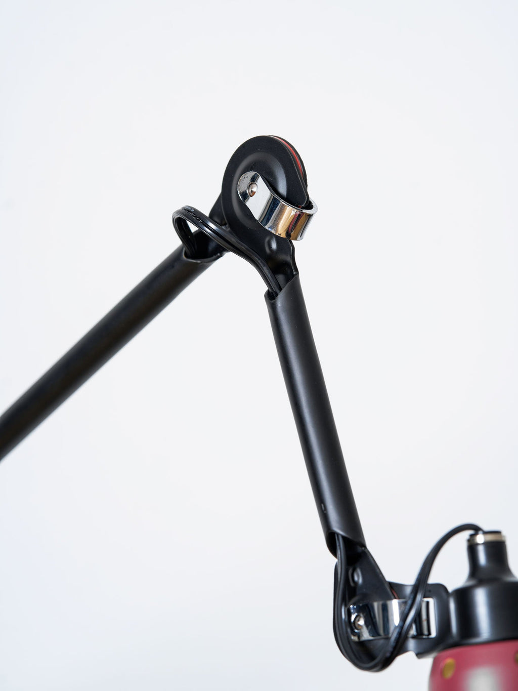 Close view of the black wall bracket and pivot joint of this Clérachic wall light, with the cable running down beside the bar.