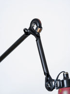 Close view of the black wall bracket and pivot joint of this Clérachic wall light, with the cable running down beside the bar.