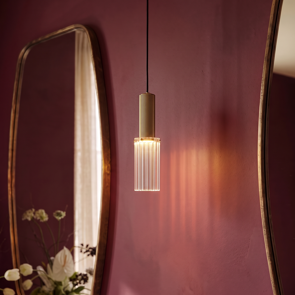 Close view of the Clérachic ribbed glass pendant with a fluted brass-toned top, casting amber light on a plum wall
