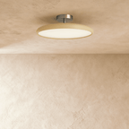 Clérachic slim round ceiling light with a cream rim and glowing white diffuser on a brushed nickel stem, on a limewash ceiling.