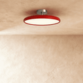 Clérachic slim round ceiling light with a glossy red rim and glowing white diffuser, on a brushed nickel stem.
