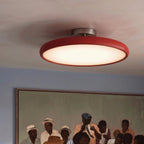 Clérachic red round ceiling light lit close up, with a soft white diffuser beneath a framed painting on a blue wall.