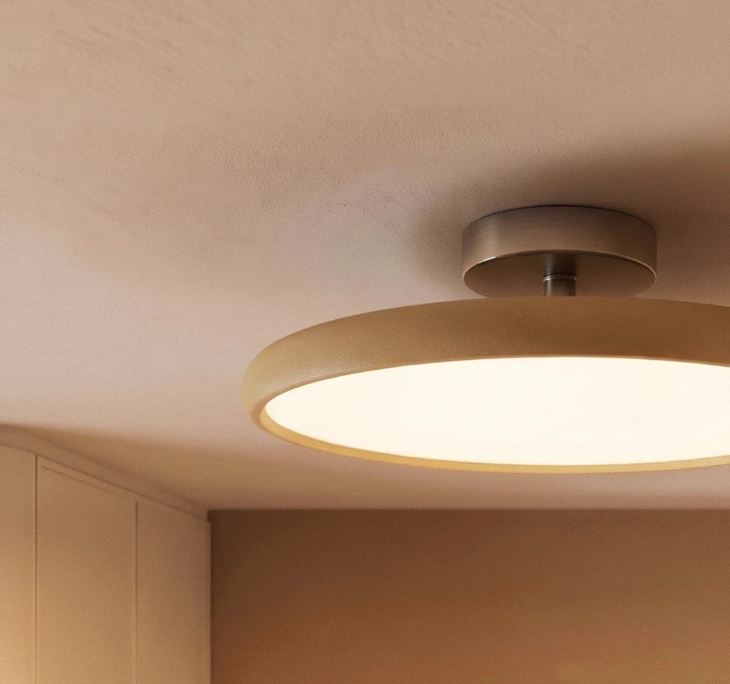 Clérachic close view of the cream round ceiling light, showing its soft leather-like rim, white diffuser and metal canopy.