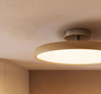 Clérachic close view of the cream round ceiling light, showing its soft leather-like rim, white diffuser and metal canopy.