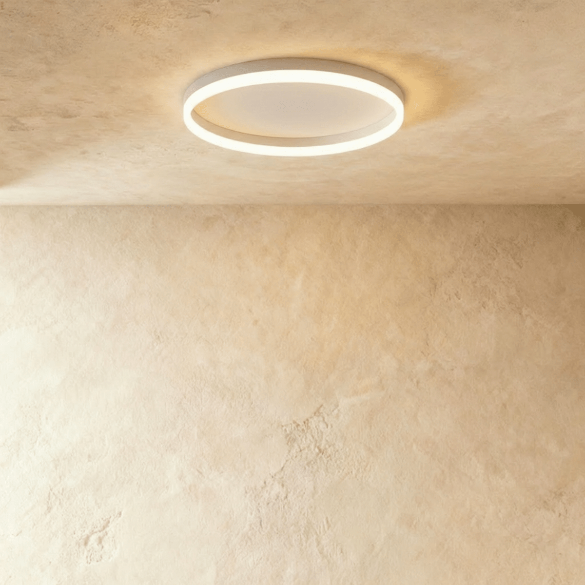 Clérachic slim white round ceiling light with a glowing acrylic ring and pale centre disc, flush on limewash plaster.