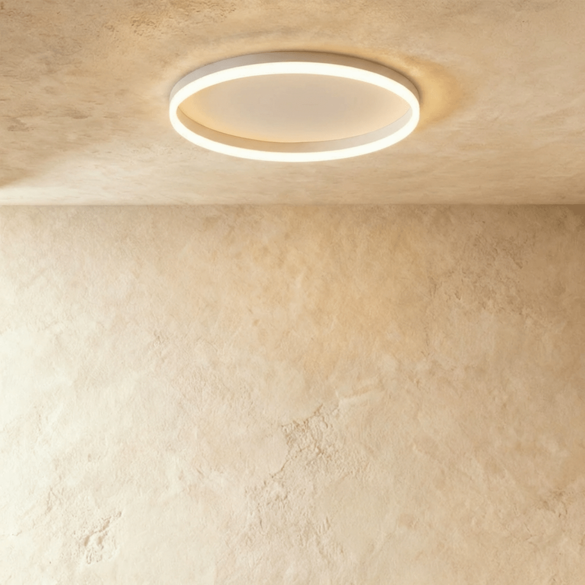Clérachic slim white round ceiling light with a glowing acrylic ring and pale centre disc, flush on limewash plaster.