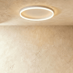 Clérachic slim white round ceiling light with a glowing acrylic ring and pale centre disc, flush on limewash plaster.