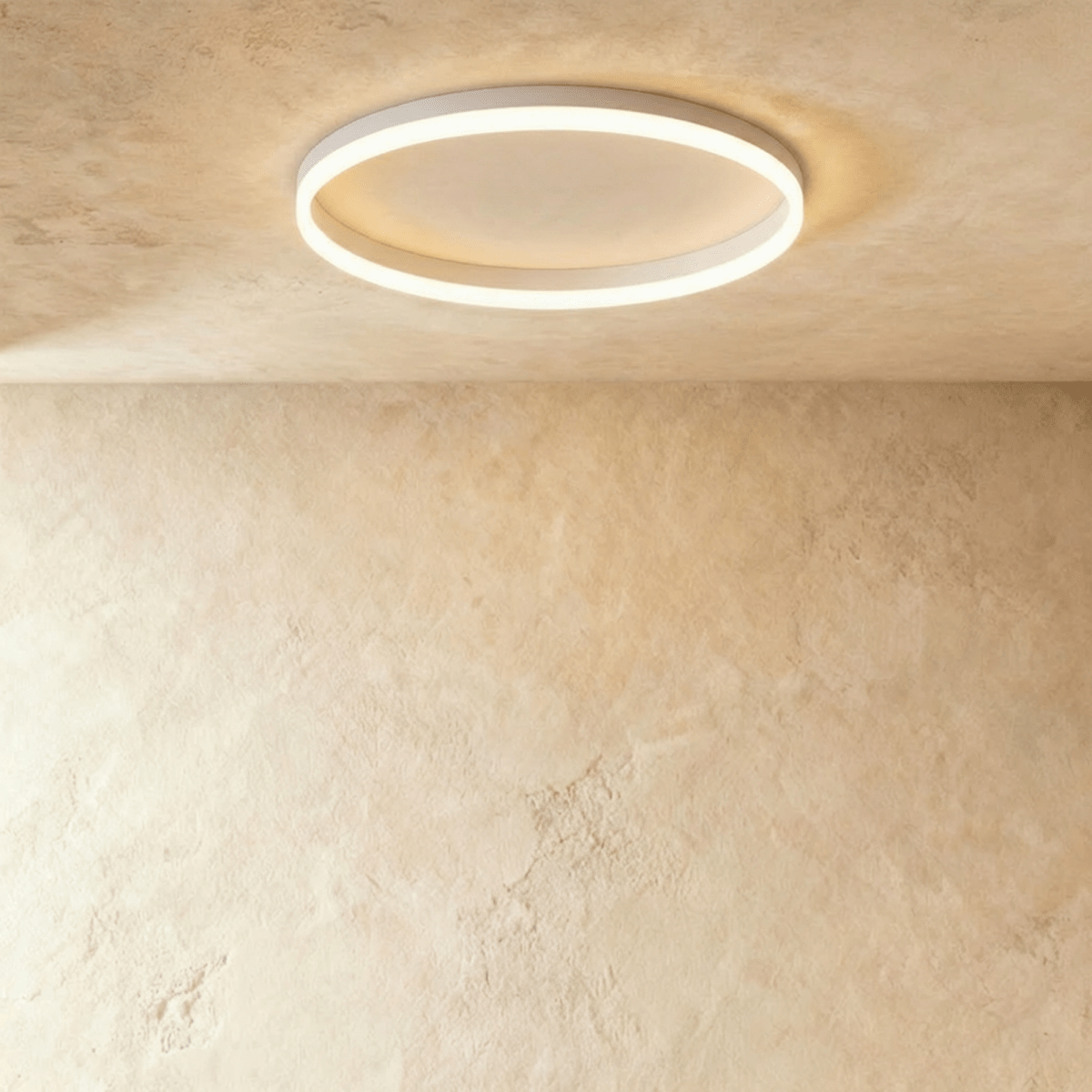 Clérachic slim white round ceiling light with a glowing acrylic ring and pale centre disc, flush on limewash plaster.
