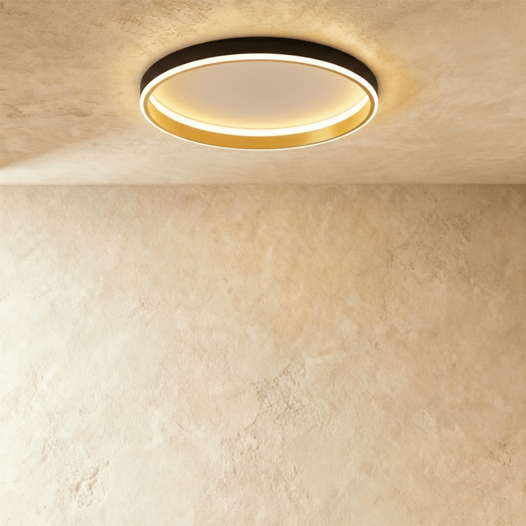 Clérachic black round ceiling light with a glowing acrylic ring and a brushed gold inner wall, flush on limewash plaster.