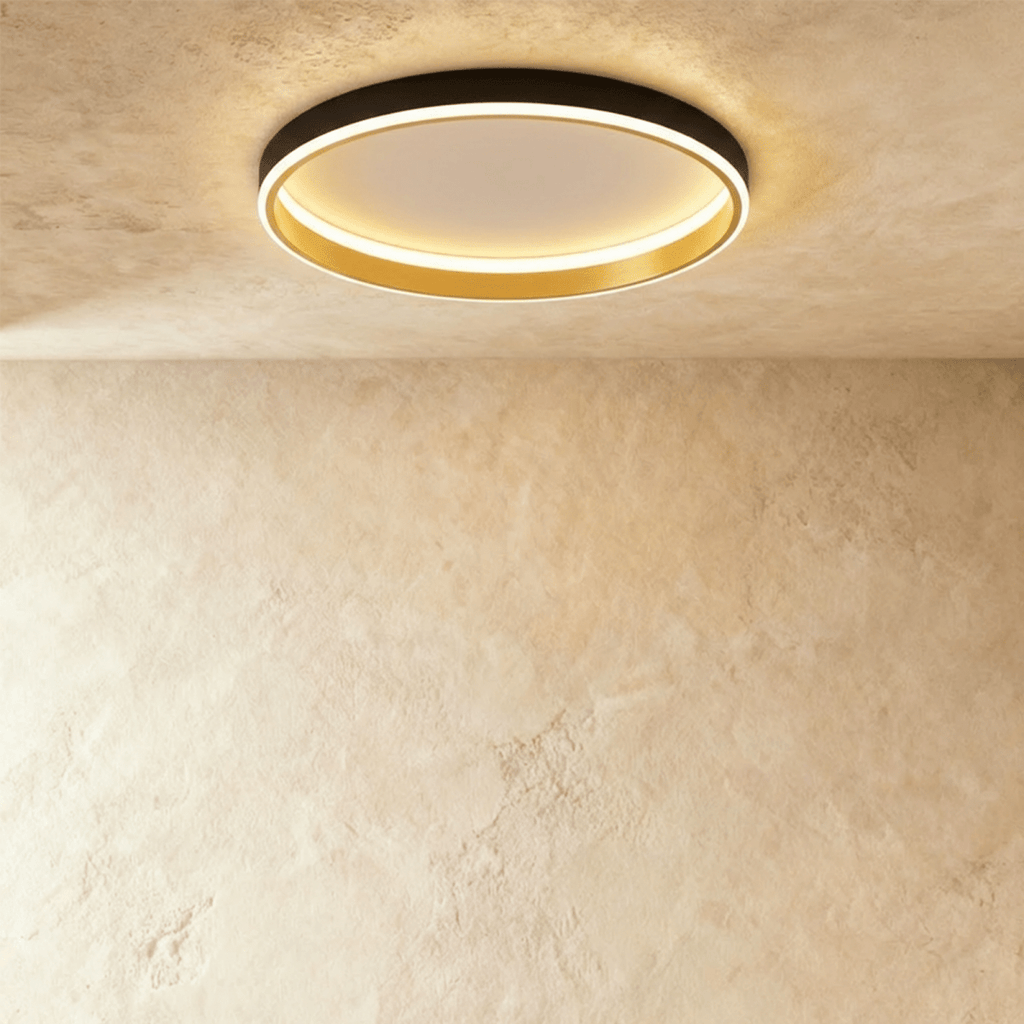 Clérachic black round ceiling light with a glowing acrylic ring and a brushed gold inner wall, flush on limewash plaster.