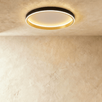 Clérachic black round ceiling light with a glowing acrylic ring and a brushed gold inner wall, flush on limewash plaster.