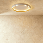 Clérachic white round ceiling light with a glowing acrylic ring and a brushed gold inner wall, flush on limewash plaster.