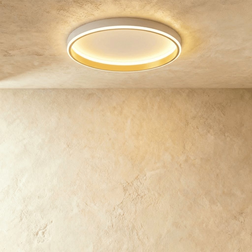 Clérachic white round ceiling light with a glowing acrylic ring and a brushed gold inner wall, flush on limewash plaster.