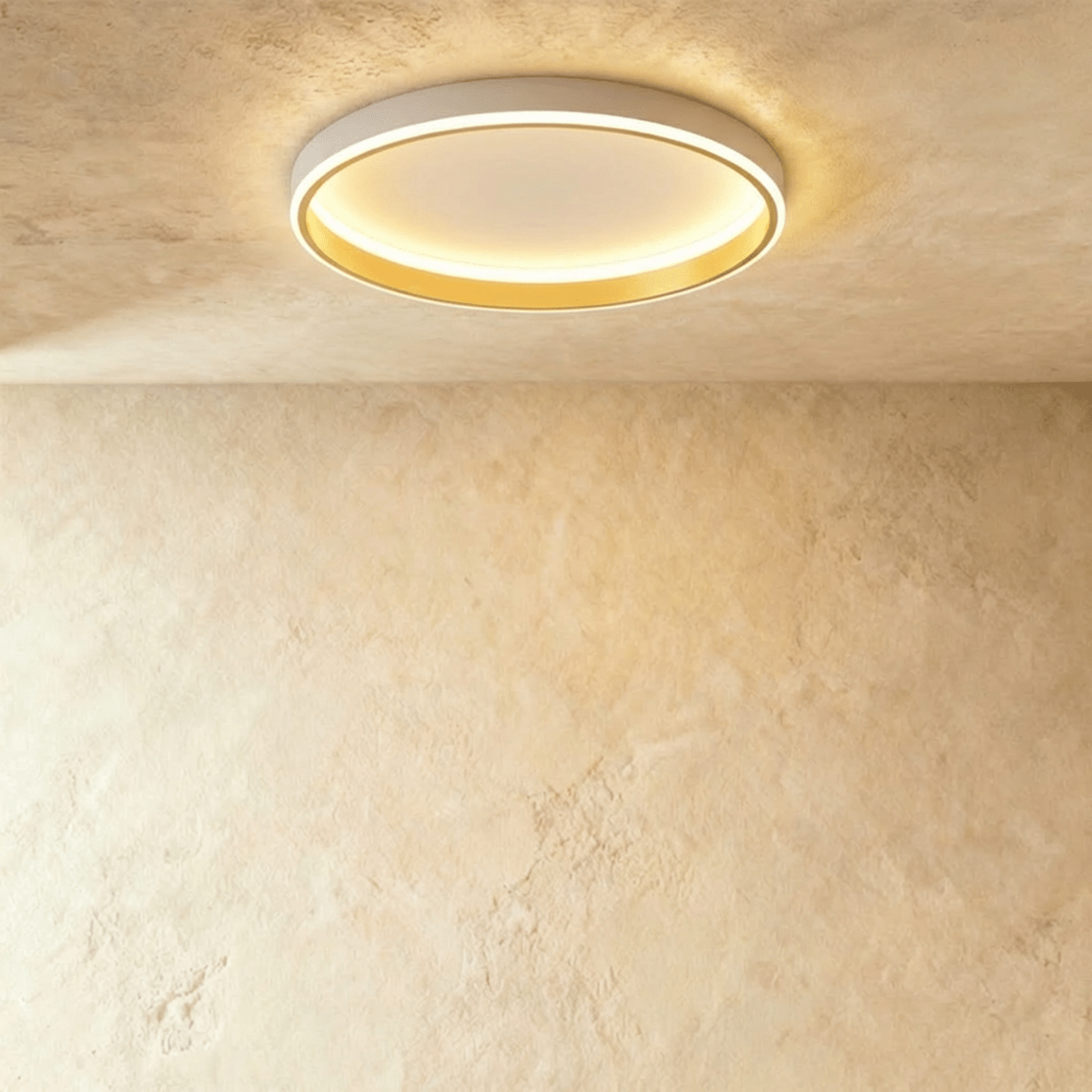 Clérachic white round ceiling light with a glowing acrylic ring and a brushed gold inner wall, flush on limewash plaster.