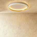 Clérachic white round ceiling light with a glowing acrylic ring and a brushed gold inner wall, flush on limewash plaster.