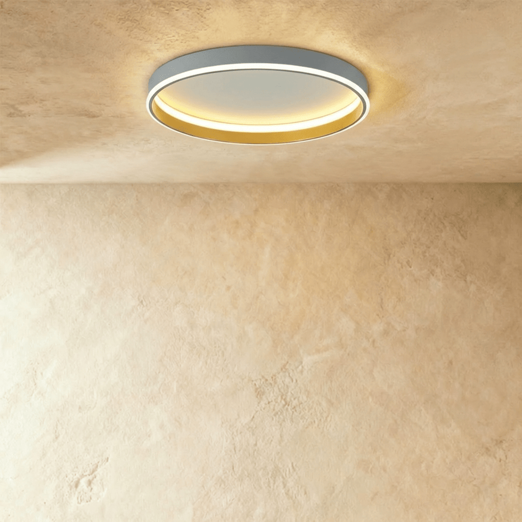 Clérachic grey round ceiling light with a glowing acrylic ring and a brushed gold inner wall, flush on limewash plaster.