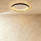 Clérachic black round ceiling light with a glowing acrylic ring and a brushed gold inner wall, flush on limewash plaster.