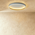 Clérachic grey round ceiling light with a glowing acrylic ring and a brushed gold inner wall, flush on limewash plaster.