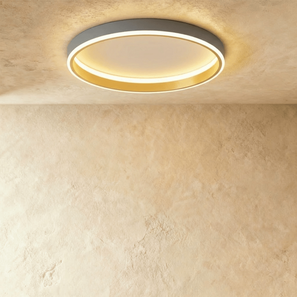 Clérachic grey round ceiling light with a glowing acrylic ring and a brushed gold inner wall, flush on limewash plaster.