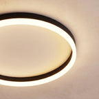 Clérachic close view of a black round ceiling light, its frosted acrylic ring glowing around a pale recessed centre disc.