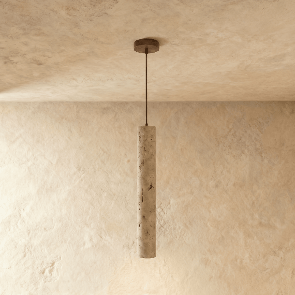 Clérachic slim travertine-look cylinder pendant hanging from a round bronze ceiling plate in a mid length on limewash.