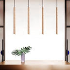 Clérachic four slim stone-look cylinder pendants in a straight row above a table with a leafy stem in a vase.