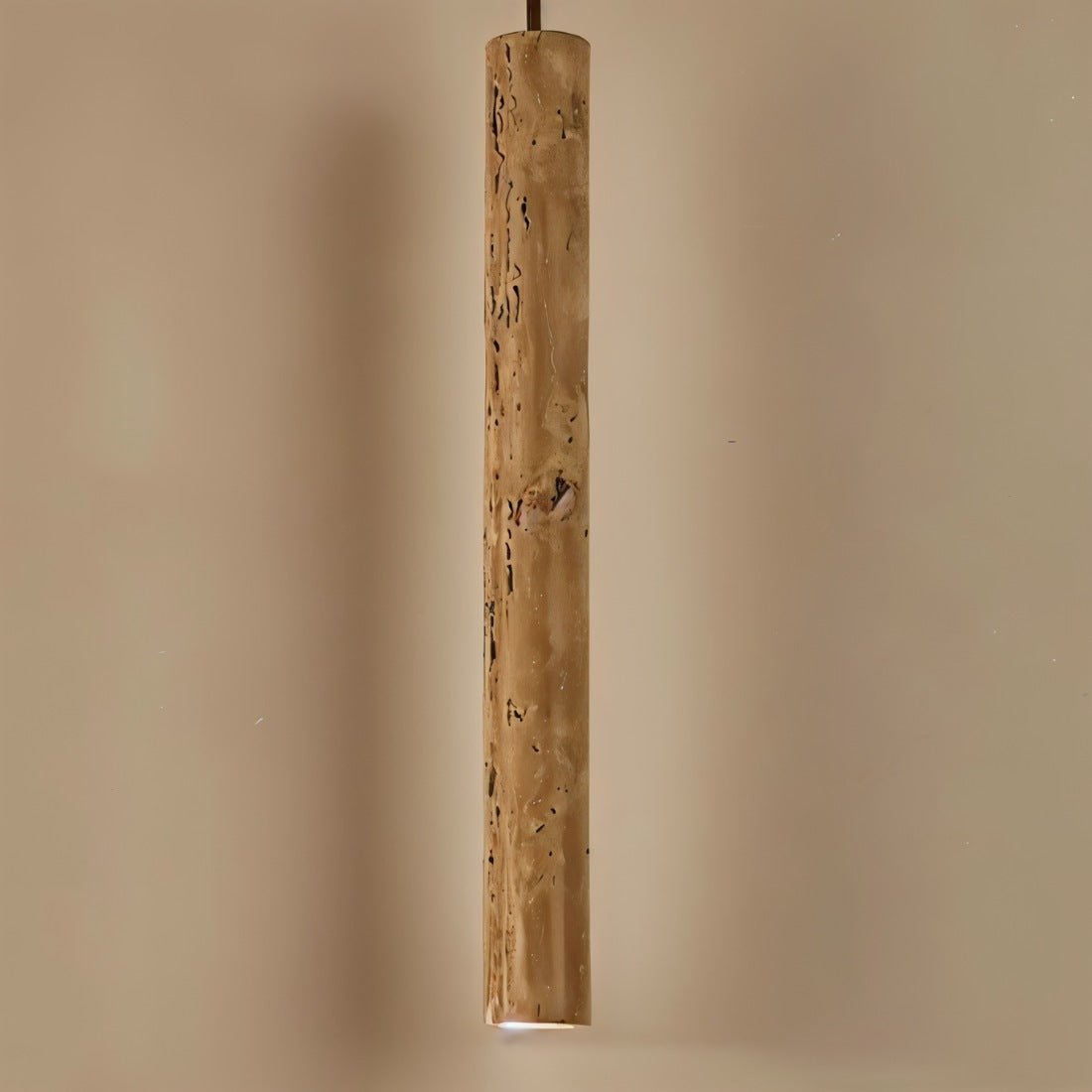 Clérachic lit slim travertine-look cylinder pendant close up, warm pitted stone grain and a glowing opening at the base.