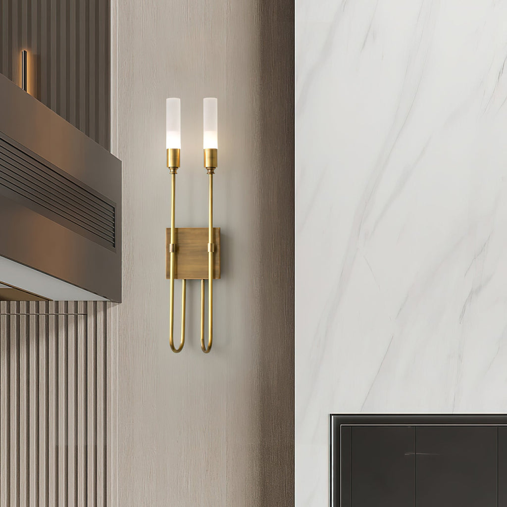 Distant view of a brass two-light Clérachic sconce on a pale panelled wall beside a marble-look panel and a dark metal vent.