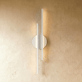 Clérachic wall light with two slim white light bars of different lengths on a round white backplate, glowing on plaster