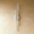 Clérachic wall light with two slim white bars on a round white backplate, switched off against a warm plaster wall
