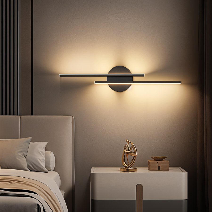 Clérachic black wall light with two slim bars laid horizontally, lit warm above a white bedside table and a gold sculpture