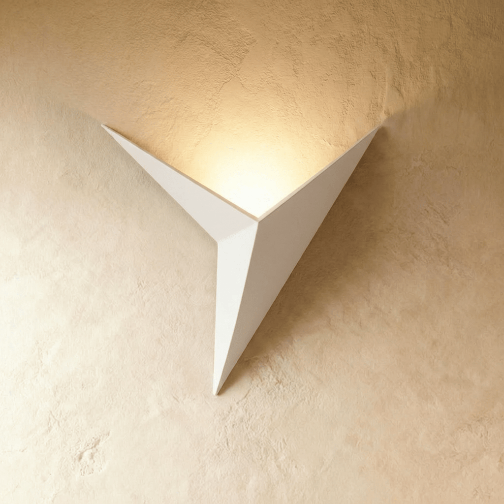 A Clérachic slim iron wall sconce in matte white casts a warm upward glow across a plaster wall corner.