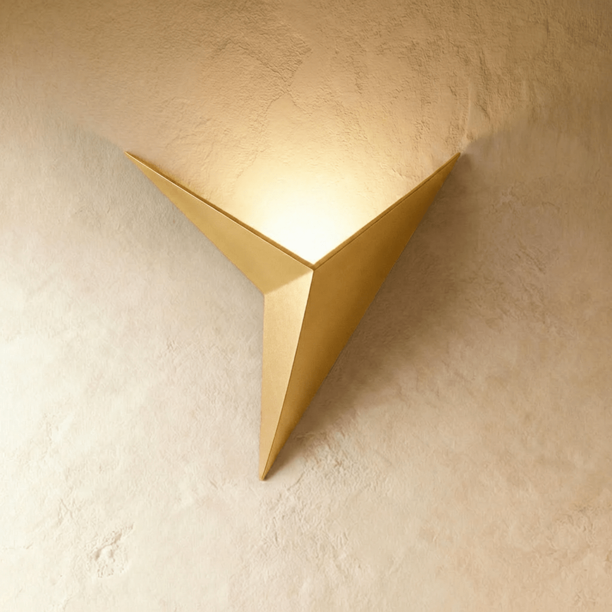 A Clérachic slim iron wall sconce in brushed gold casts a warm upward glow across a plaster wall corner.