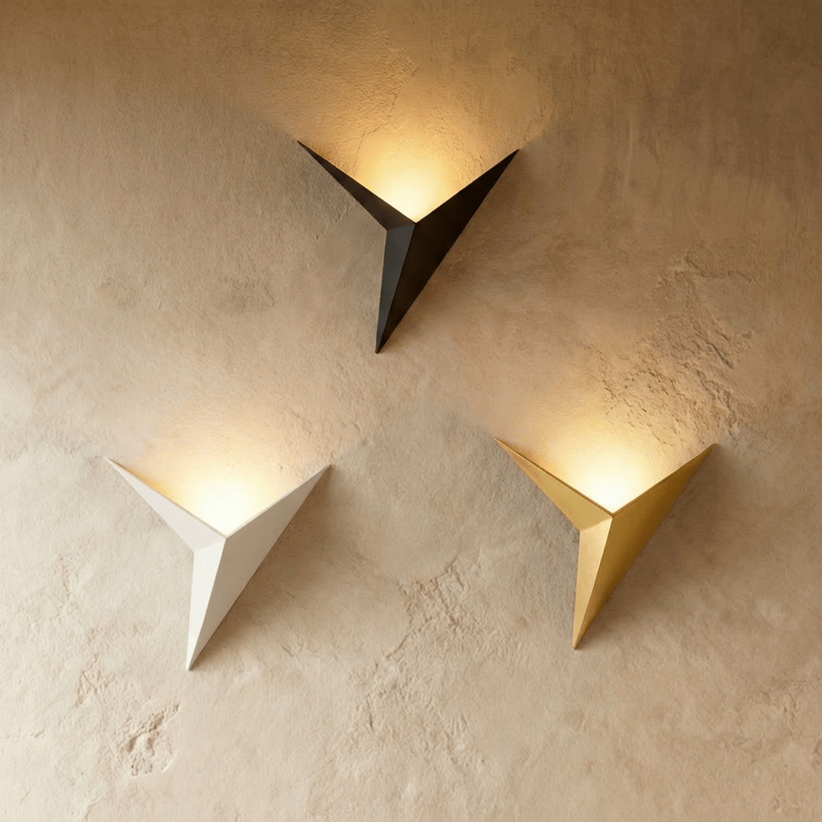 Clérachic slim iron wall sconces in black, white and gold finishes glow warm side by side on a plaster wall.