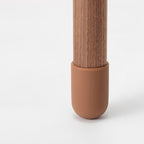 Close view of the rounded terracotta-coloured foot cap at the base of this Clérachic walnut-colour floor lamp.