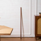 Full-height Clérachic floor lamp in walnut colour, shown unlit against a panelled wall with a herringbone floor.
