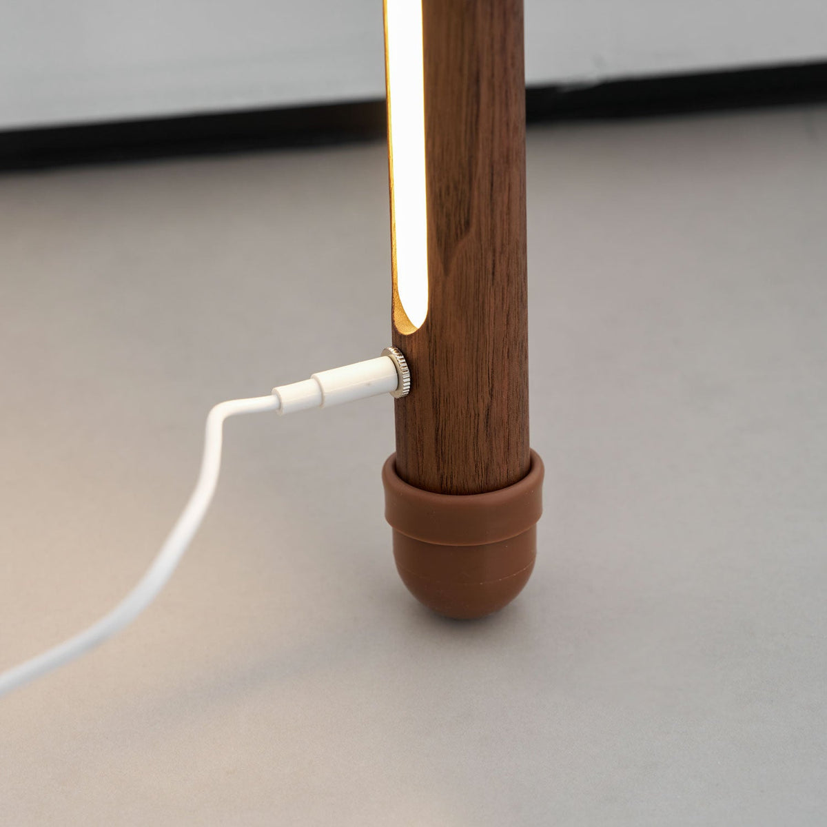 White power cable plugged into the side of this Clérachic floor lamp, just above its terracotta foot cap and light strip.