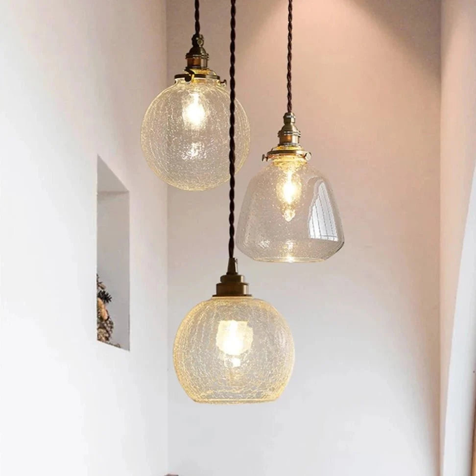 Three Clérachic glass pendants at different heights on twisted cords, two crackle globes and a clear bubbled shade.