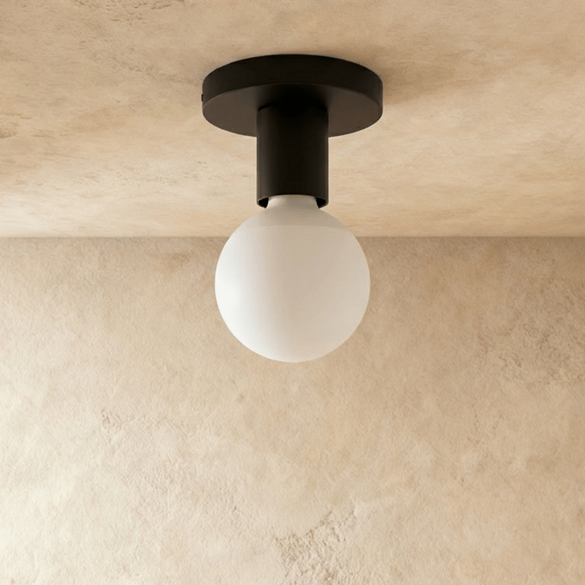 Clérachic black flush ceiling light, unlit, showing its slim round canopy, short stem and opal globe bulb on plaster.