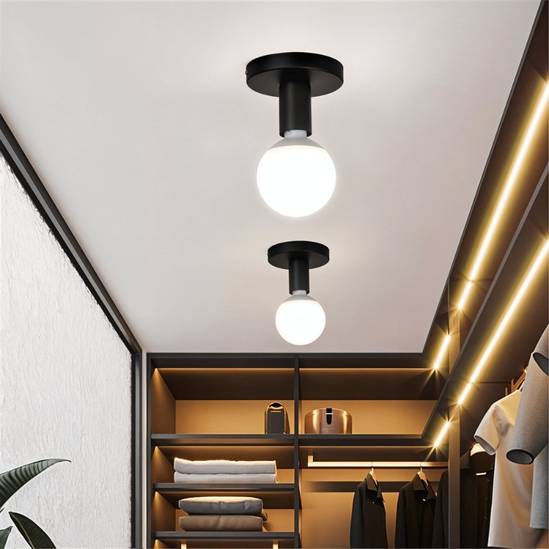 Two Clérachic black ceiling lights with glowing white globes hung over a walk-in wardrobe with lit shelving and rails.