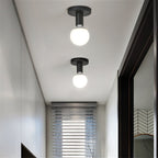 Two Clérachic black ceiling lights with white globe bulbs lit in a narrow white hallway beside a blind-covered window.