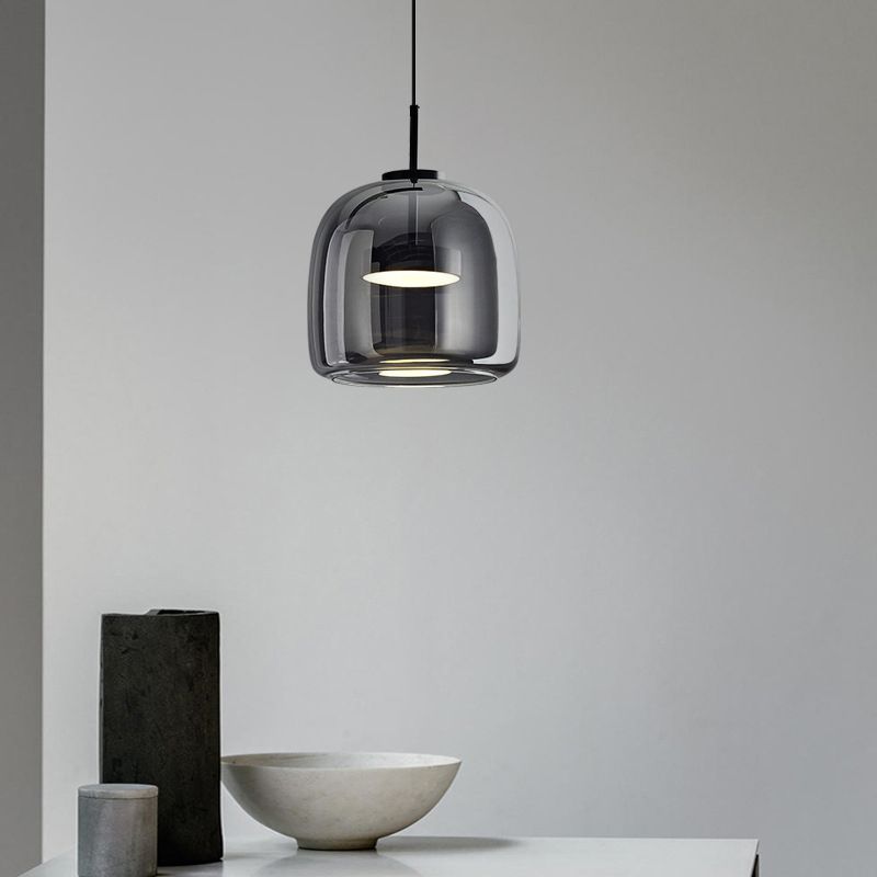 Clérachic smoke gray glass dome pendant seen close over a console, the tinted glass showing the twin frosted discs inside.