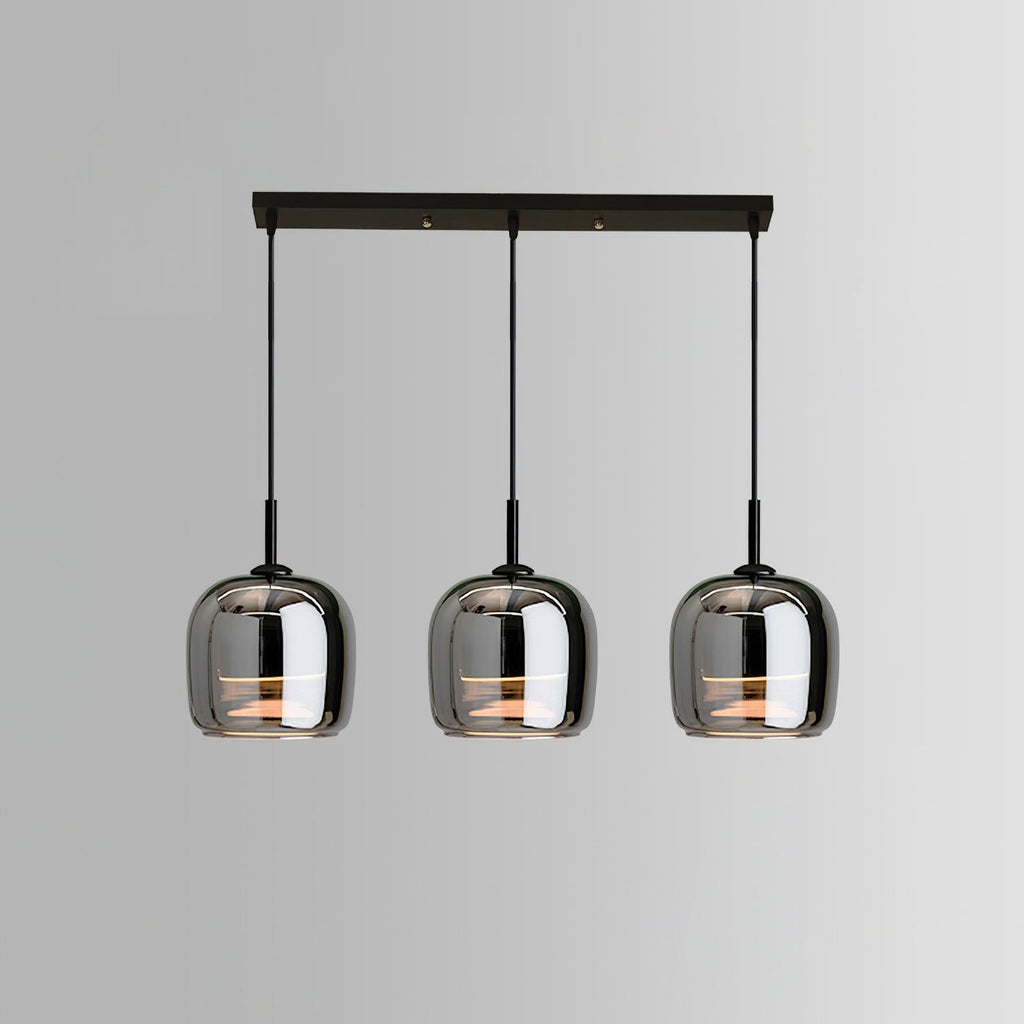 Studio view of the Clérachic pendant in its 3-head linear bar version, three smoke gray domes lit warm beneath a black bar canopy.