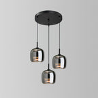 The Clérachic pendant in its round-cluster version, three smoke gray glass domes dropped at staggered heights from a black disc canopy.
