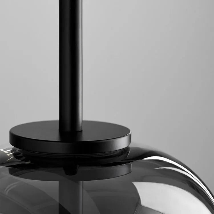 Detail of the Clérachic pendant's matte black stem and collar seated on top of the smoke gray blown-glass dome.