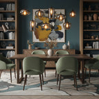 Smoke glass shades of this Clérachic pendant hang in front of a teal wall and bookshelves above a table with green chairs.