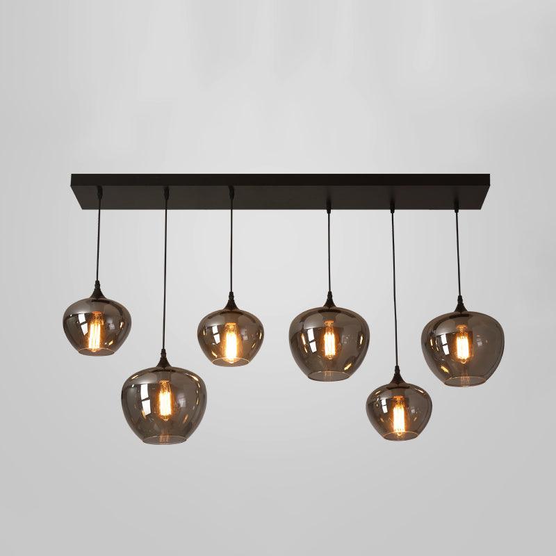 Six smoke glass globes hang from a long black canopy on this Clérachic pendant, shown lit on a pale grey backdrop.