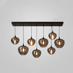 Eight smoke glass globes of this Clérachic pendant hang at staggered heights from a black bar canopy on a grey backdrop.