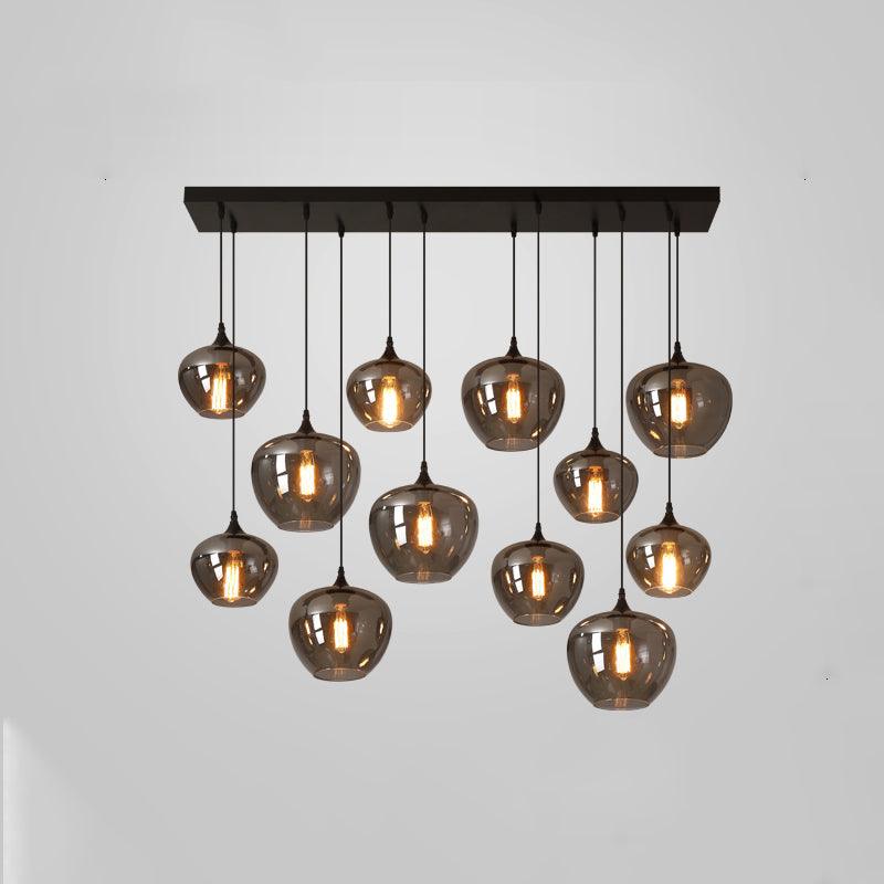 A dense Clérachic pendant cluster of twelve smoke glass globes under a black canopy, lit on a plain grey backdrop.