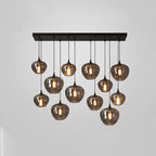 A dense Clérachic pendant cluster of twelve smoke glass globes under a black canopy, lit on a plain grey backdrop.